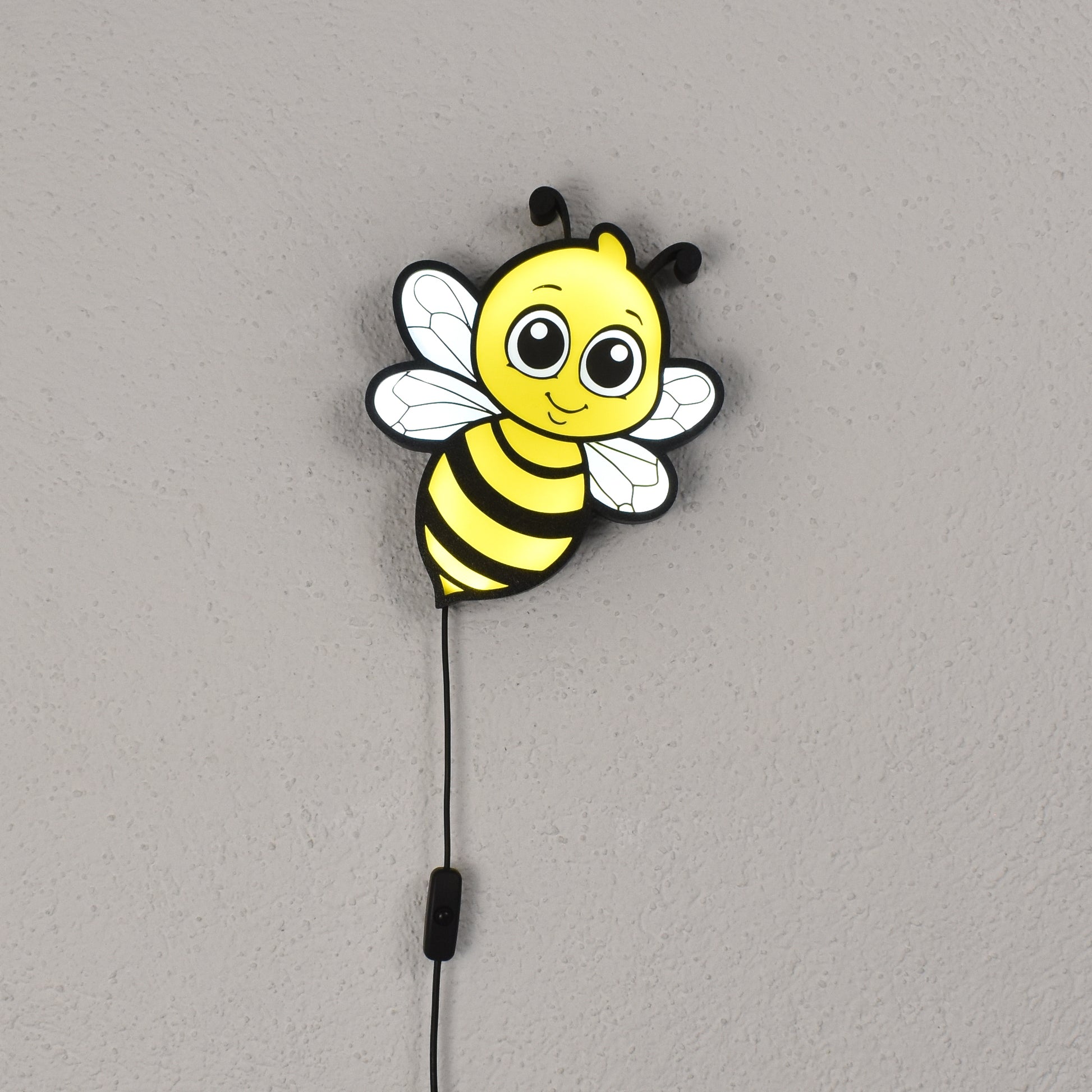 Bienenförmige LED-Wandleuchte leuchtet an einer weißen Wand – süßes Nachtlicht für Kinder