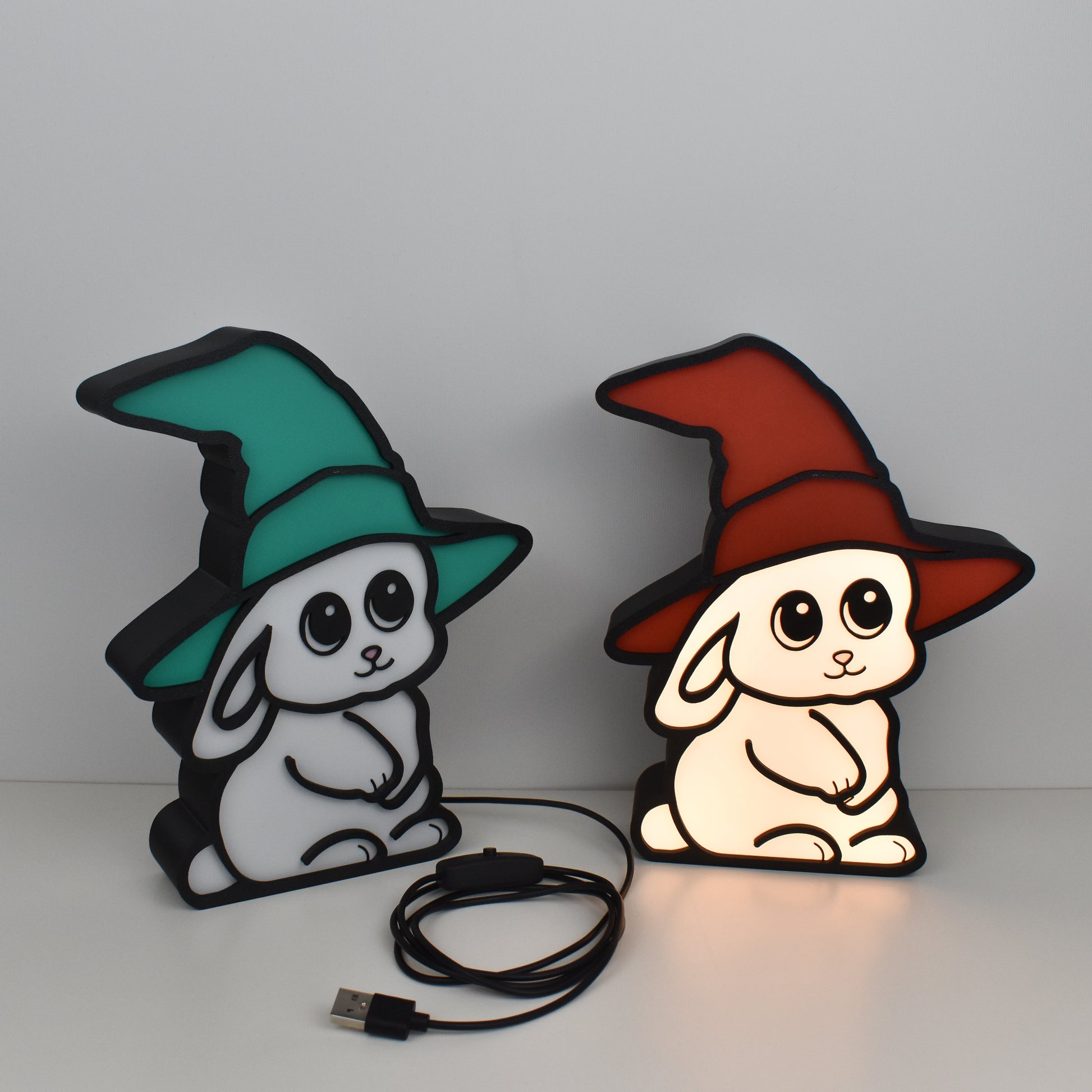 Zwei LED-Nachtlichter Zauberhase mit Hexenhut in Grün und Rot – eine Lampe leuchtend, eine ausgeschaltet, mit USB-Kabel und Schalter, ideal fürs Kinderzimmer oder als Geschenk für Kinder
