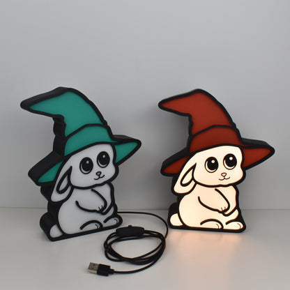 Zwei LED-Nachtlichter Zauberhase mit Hexenhut in Grün und Rot – eine Lampe leuchtend, eine ausgeschaltet, mit USB-Kabel und Schalter, ideal fürs Kinderzimmer oder als Geschenk für Kinder